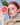 Red-haired woman holding a halved grapefruit to her face with green leaves on a blue background
