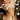 Close-up of a woman's lower face and neck, holding up Baby's Breath flowers to her chin