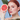 Red-haired woman holding a halved grapefruit to her face with green leaves on a blue background