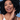 Woman with curly hair smiling, touching face, on a blue background
