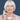 Elderly woman with white hair applying cream to her face on a blue background.