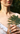  Smiling woman in a white summer dress holding a green Fern leaf with both hands